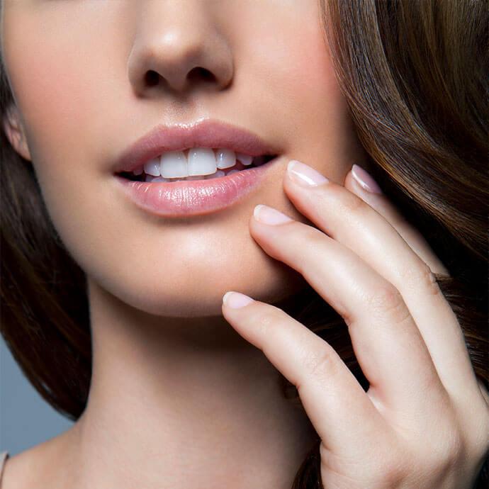 An image of a woman with half of her face visible, focusing while holding her nails near her chin