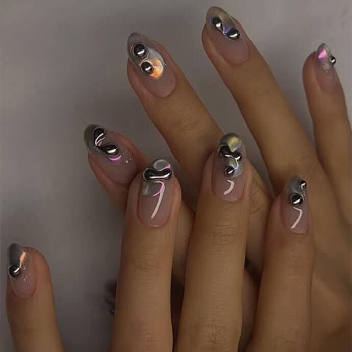 Close-up of hands with nude oval nails decorated with chrome 3D molten metal accents