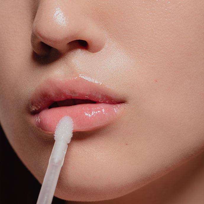 A close-up image of glossy, pouty lips with a lip gloss applicator in view