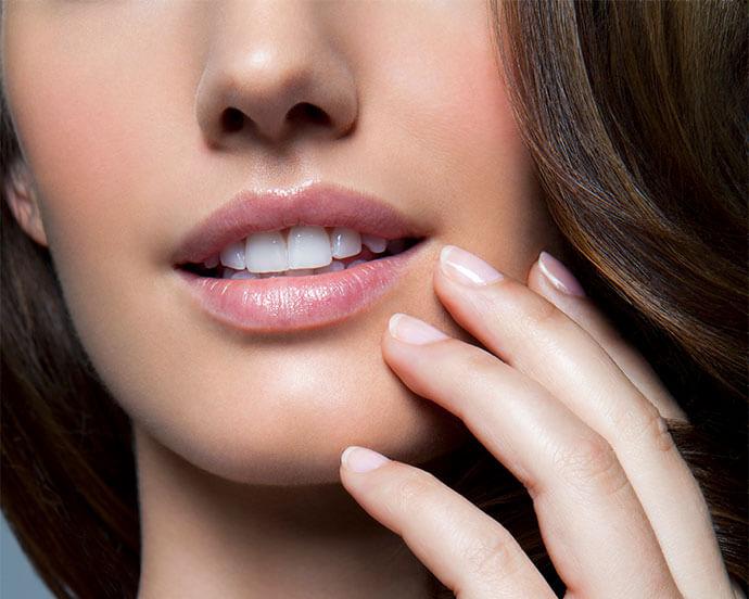 An image of a woman with half of her face visible, focusing while holding her nails near her chin