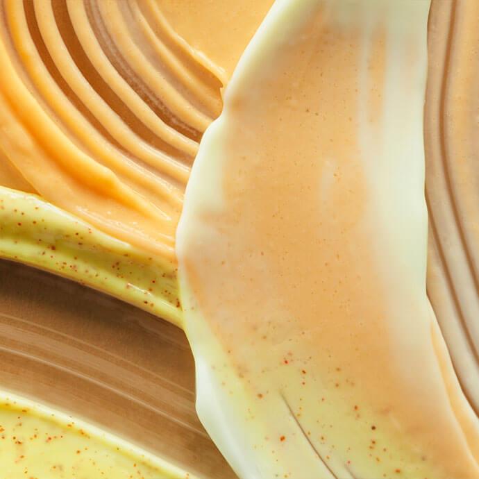 An image of a smudged, creamy texture in a mix of brown and yellow hues