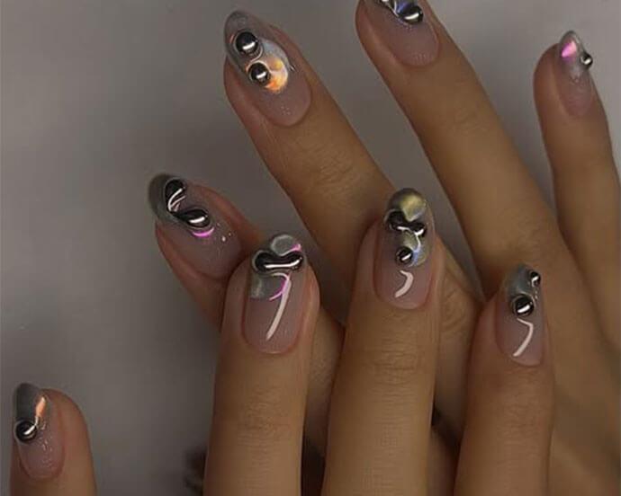 Close-up of hands with nude oval nails decorated with chrome 3D molten metal accents