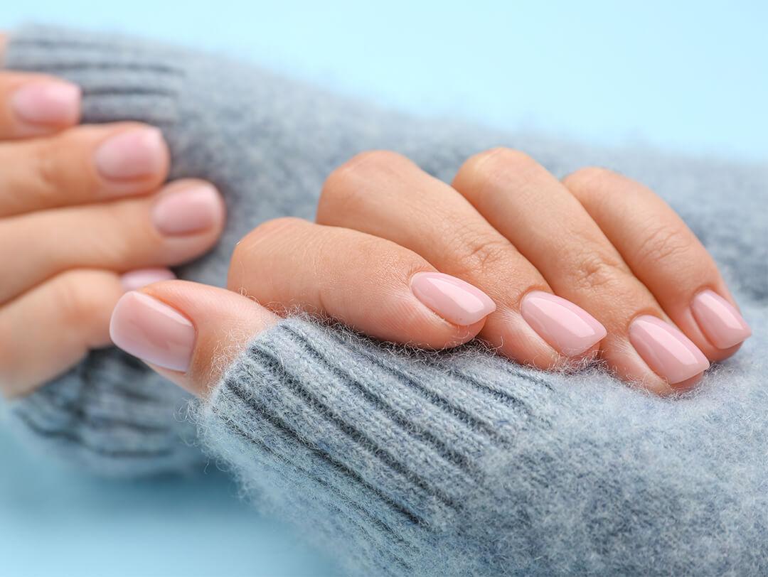 Close-up image of model's hands with nude pink mani on blue background Desktop