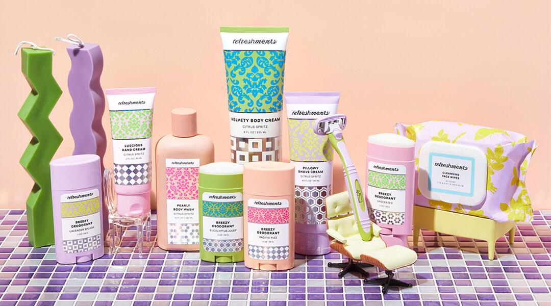 Image of Refreshments body care ingredients neatly arranged on purple and white tiles against light peach background Desktop