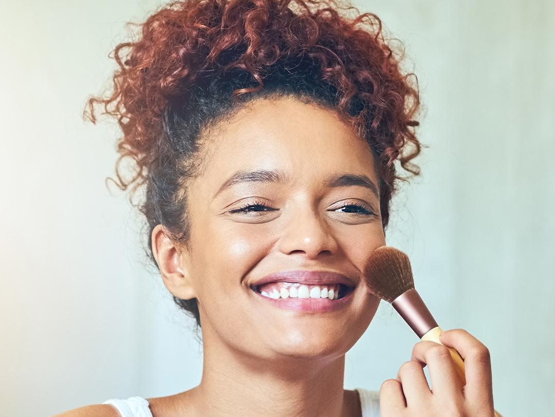 A photo of a woman using a makeup brush on her cheeks Desktop