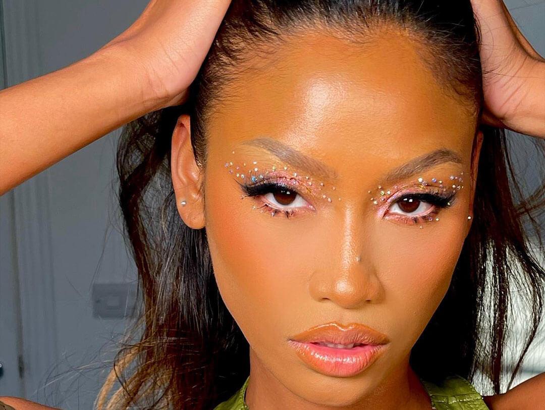 A close-up shot featuring a woman with Y2K-inspired makeup, boasting glittery eyeshadow and a fierce expression