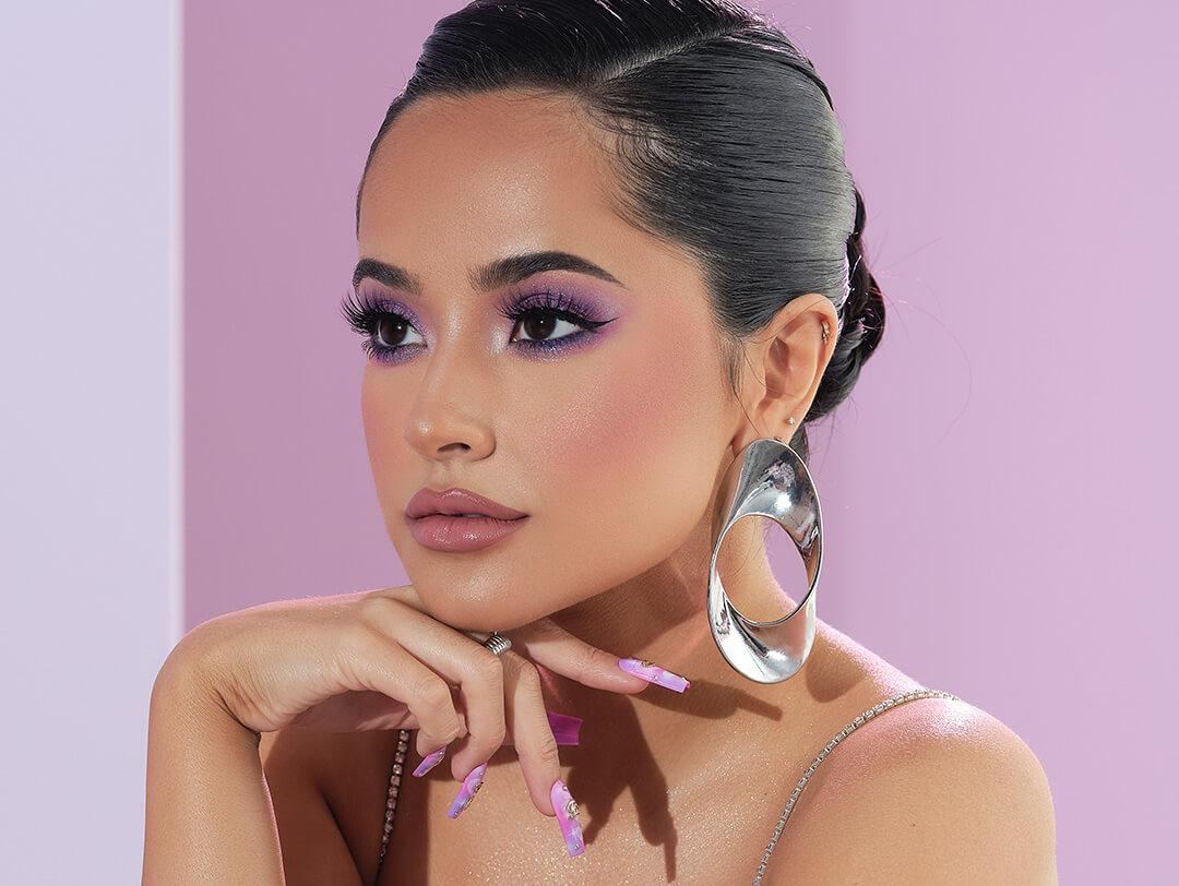 Becky G rocking pink eyeshadow and pink nails posing against pink background Desktop