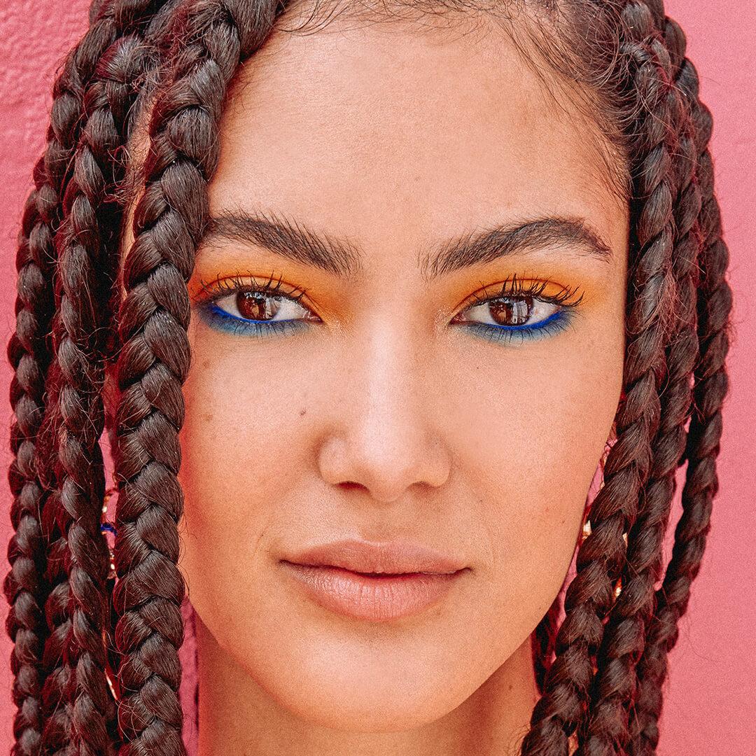 Close-up of a young woman rocking a colorful eye makeup and braided hairstyle Desktop