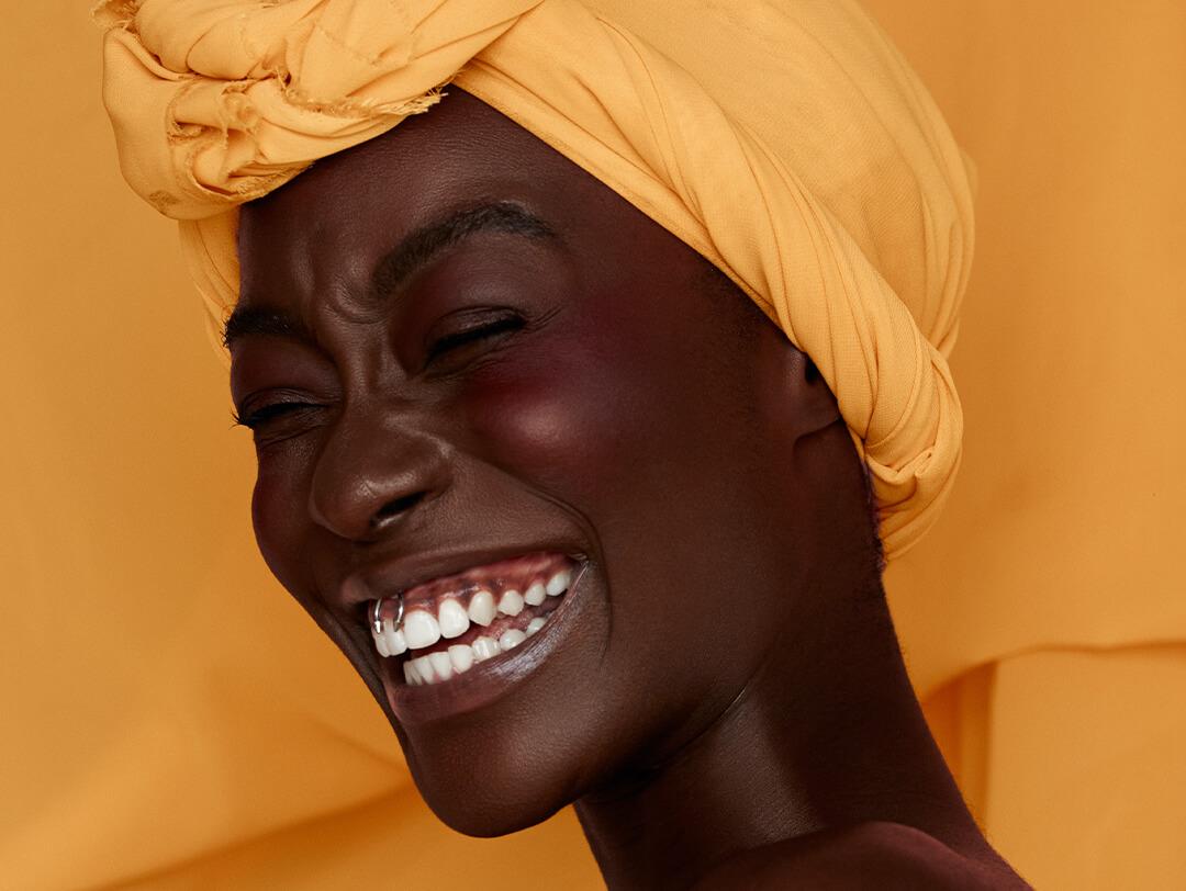 Portrait of smiling young black woman wearing yellow headscarf Desktop