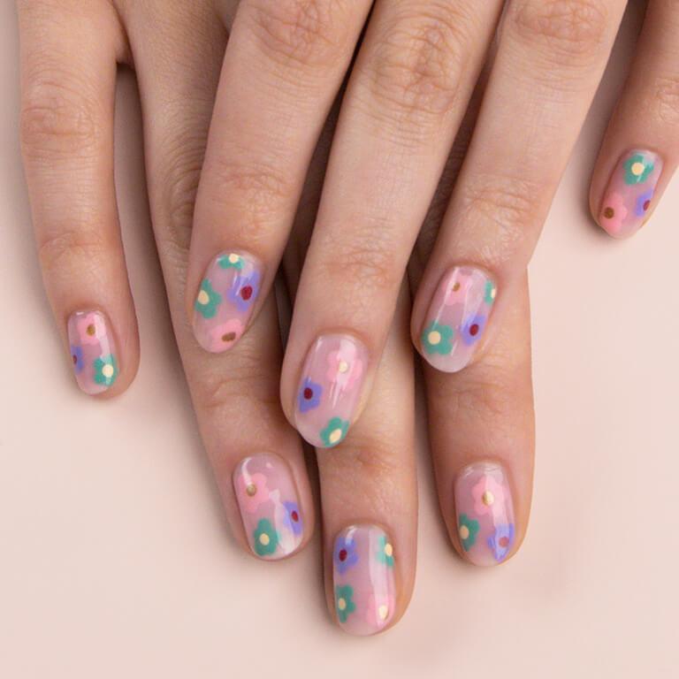 A close-up image of a model's hands with pastel colored flowers nail art Mobile