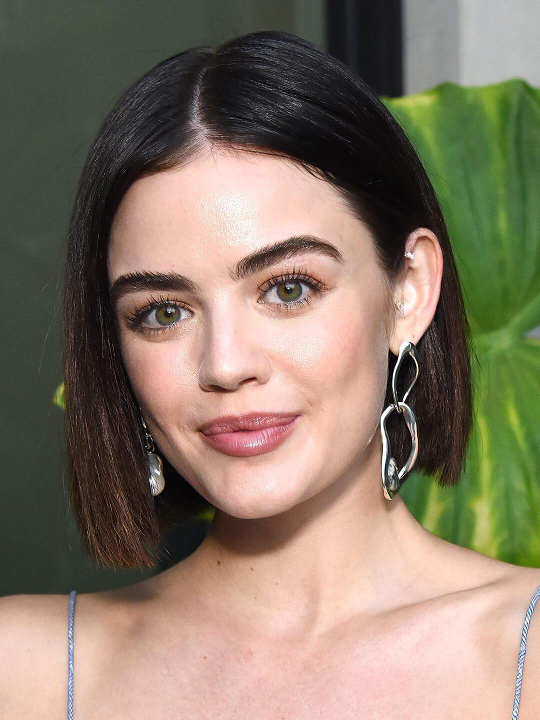 Close-up image of Lucy Hale rocking dangling earrings and a short asymmetrical bob hairstyle Mobile