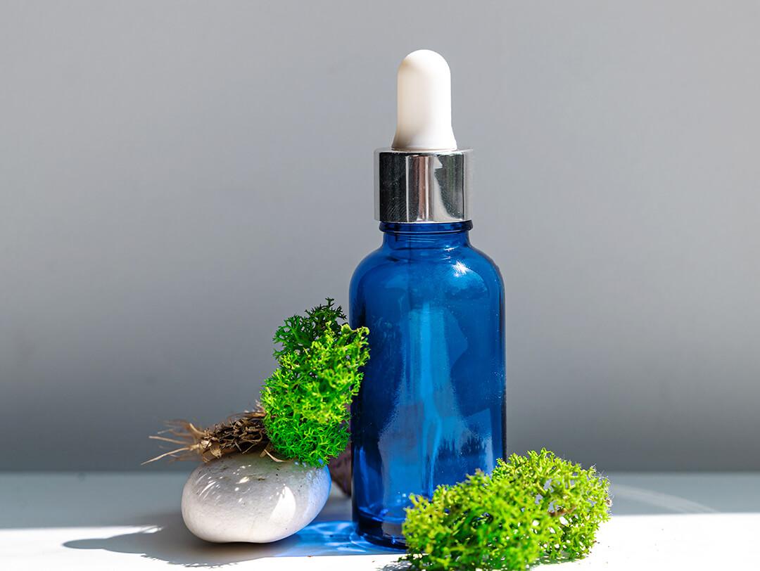 A photo of a blue serum with sea stones and sea moss on a white background