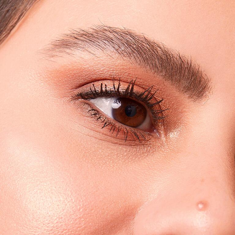 A closeup image of a model wearing shimmery, bronze eyeshadow and highlighter Mobile