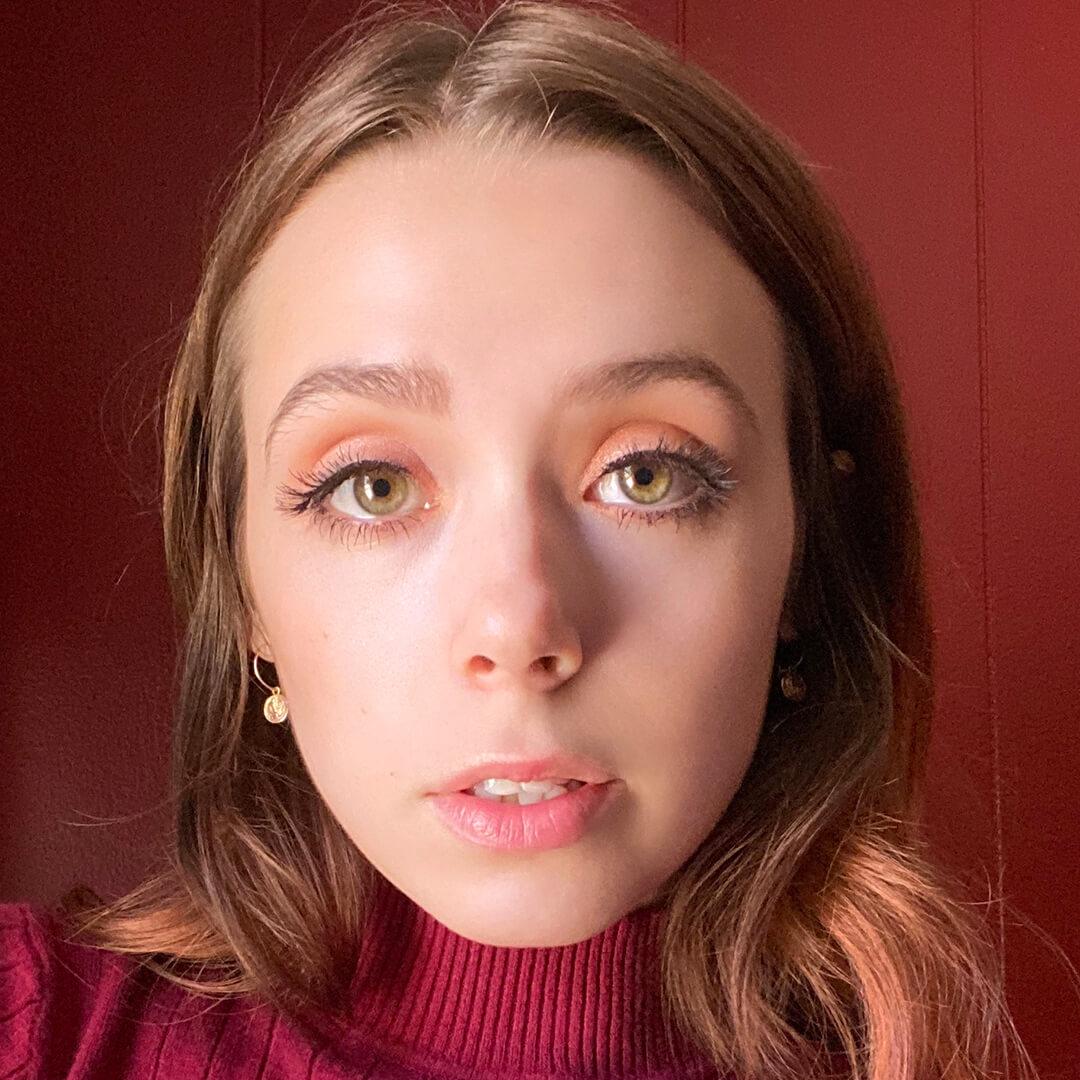Devyn Severson in a maroon turtle neck rocking a no-makeup makeup look against maroon background Desktop
