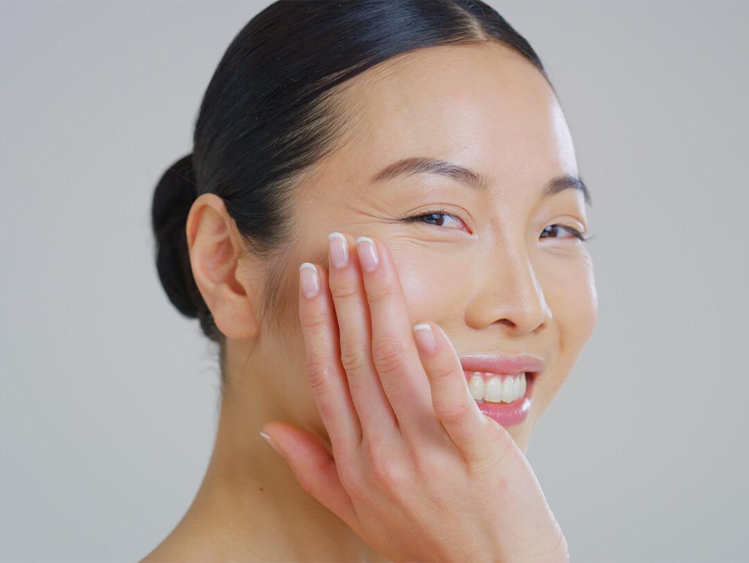 Close-up image of an Asian woman with smooth skin touching her face Desktop