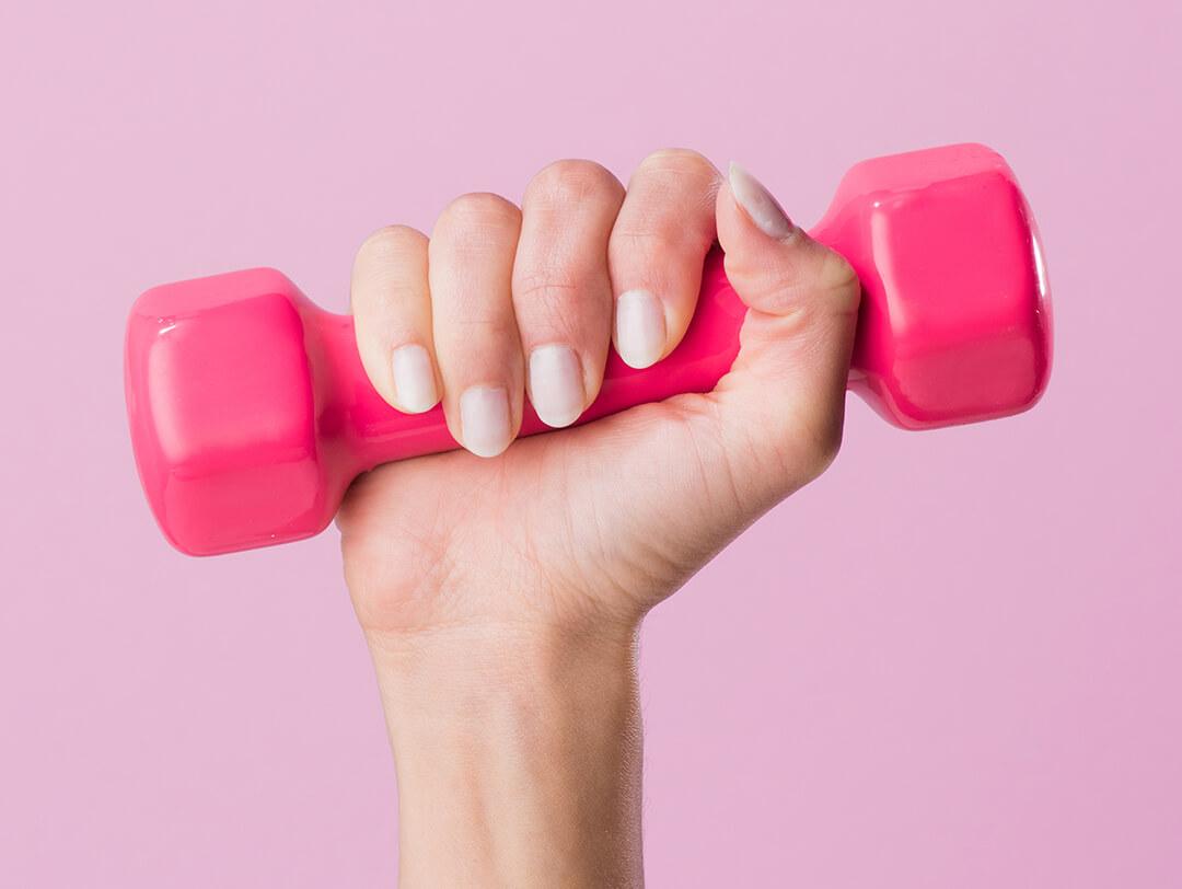 Close-up of woman's hand holding up pink dumbbell