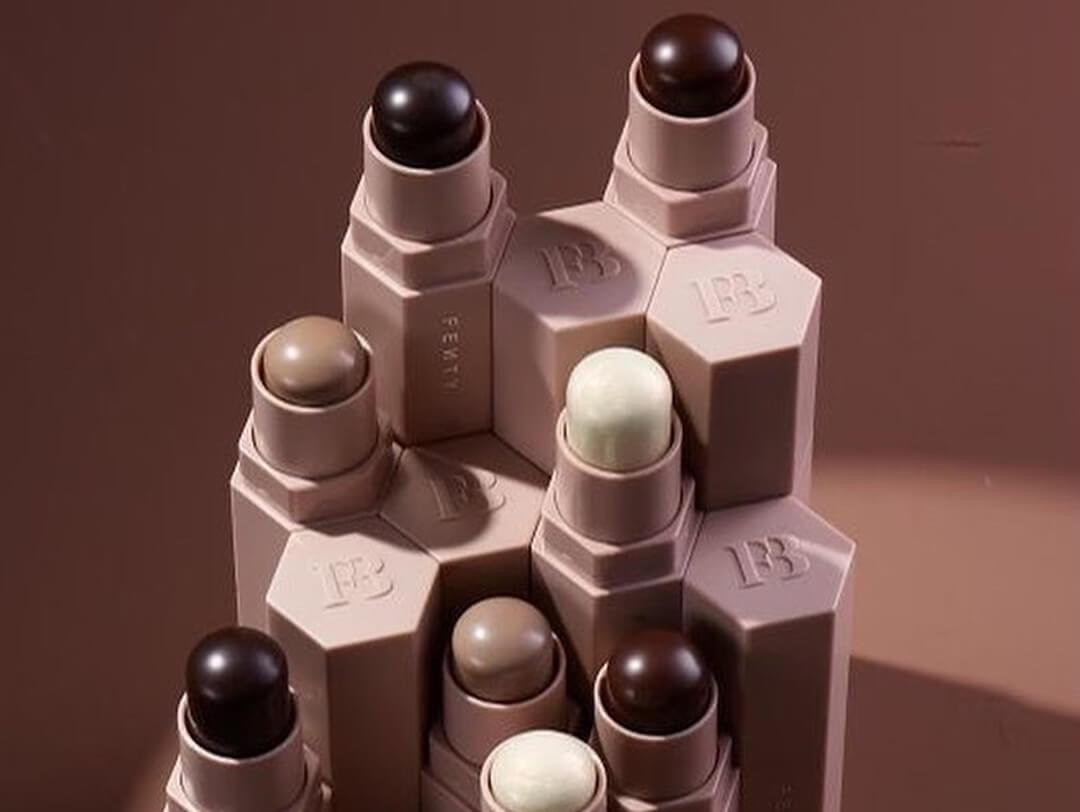 A flatlay shot of different shades of FENTY BEAUTY Match Stix Matte on a beige background Desktop