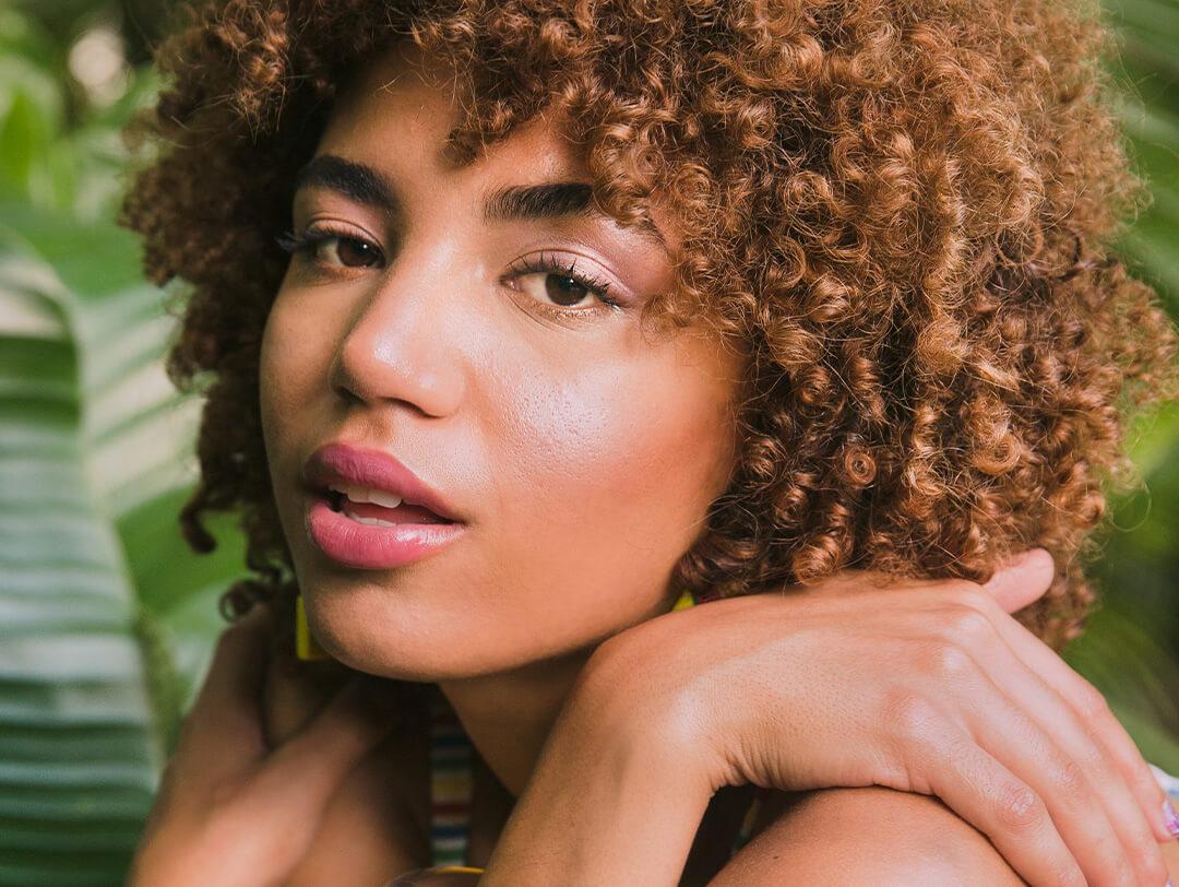 Young confident women kneeling and posing outside against leaves Desktop