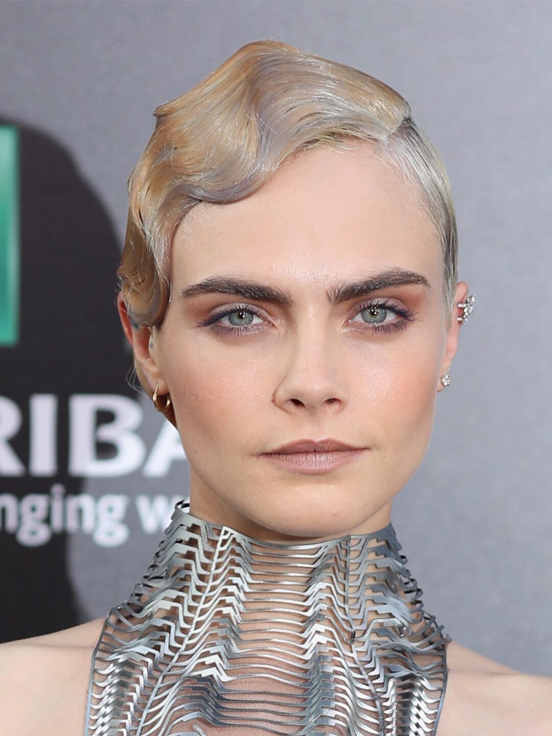 Cara Delevingne rocking a sleek and wavy short hairstyle and futuristic neck piece Mobile