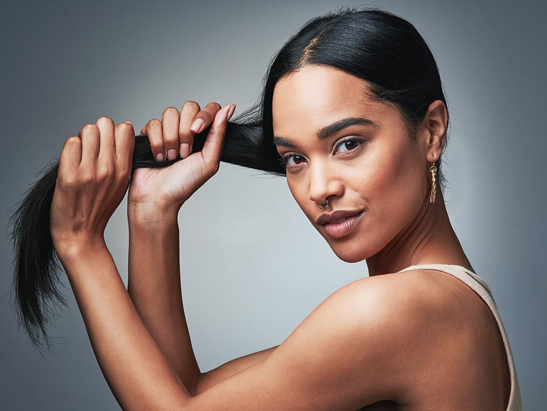 A photo of a woman holding her long, black, shiny hair with her two hands