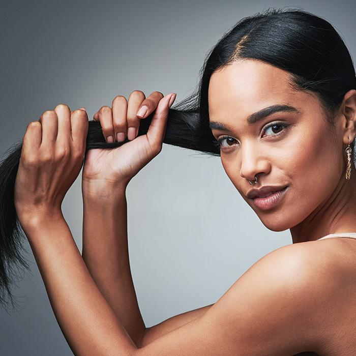 A photo of a woman holding her long, black, shiny hair with her two hands