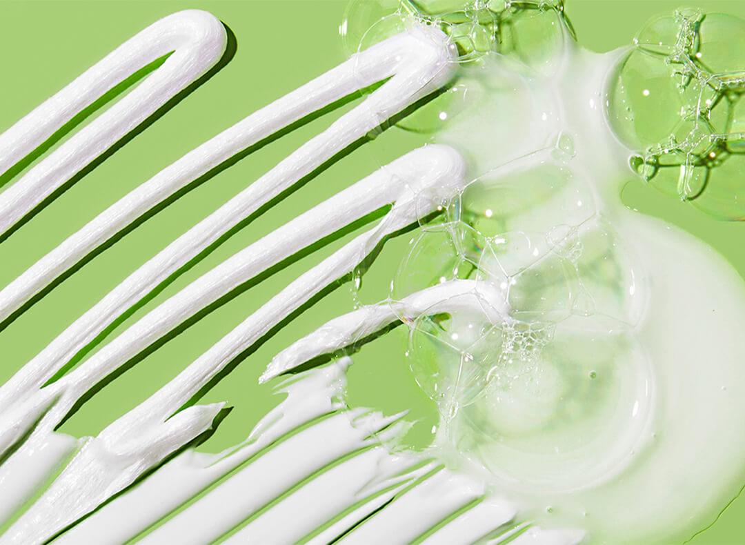 White creams of different textures swatched on green background Desktop