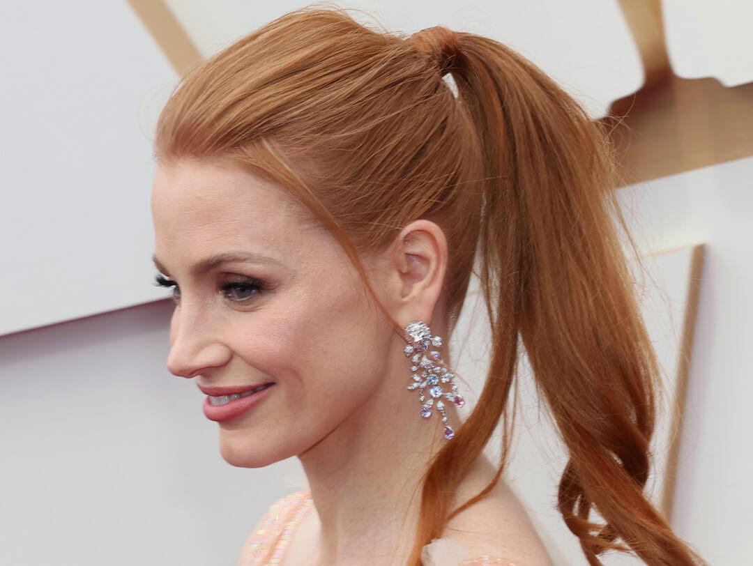 Jessica Chastain rocking a ponytail hairstyle, stone-studded dangling earrings and sequined pink dress at the red carpet Desktop