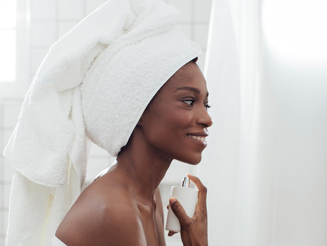 Woman applying perfume on her neck while in her bathroom Desktop