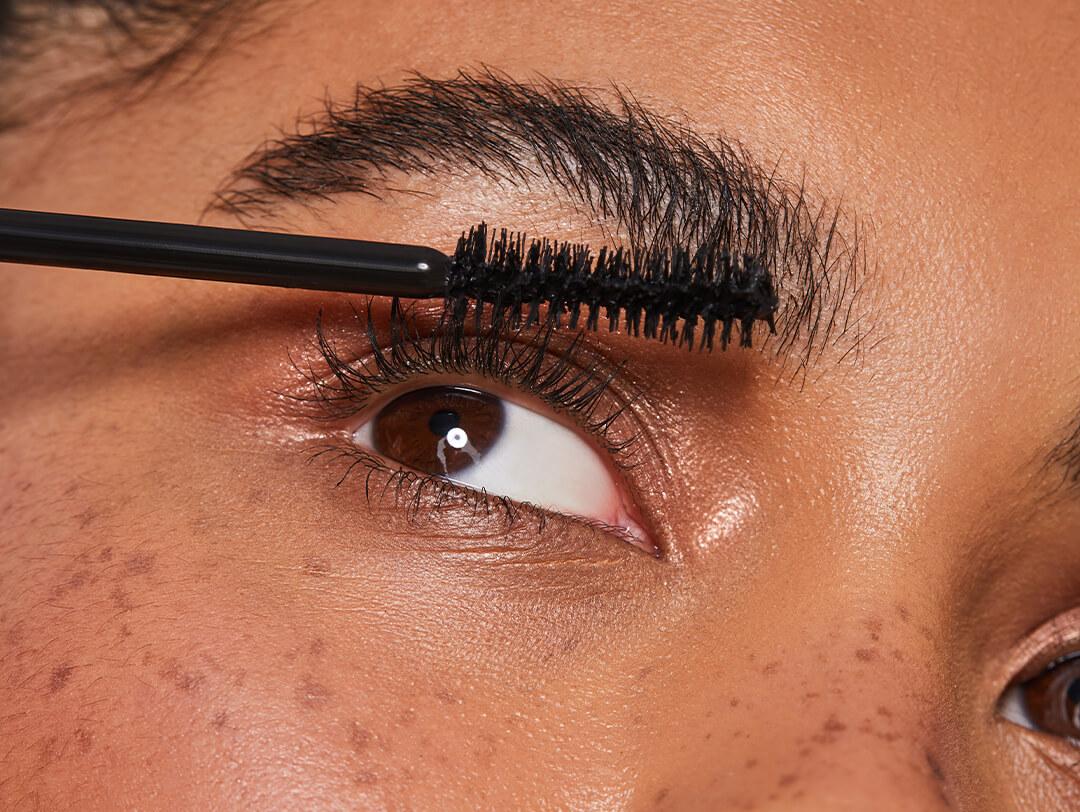 Close-up image of a model applying mascara on her lashes