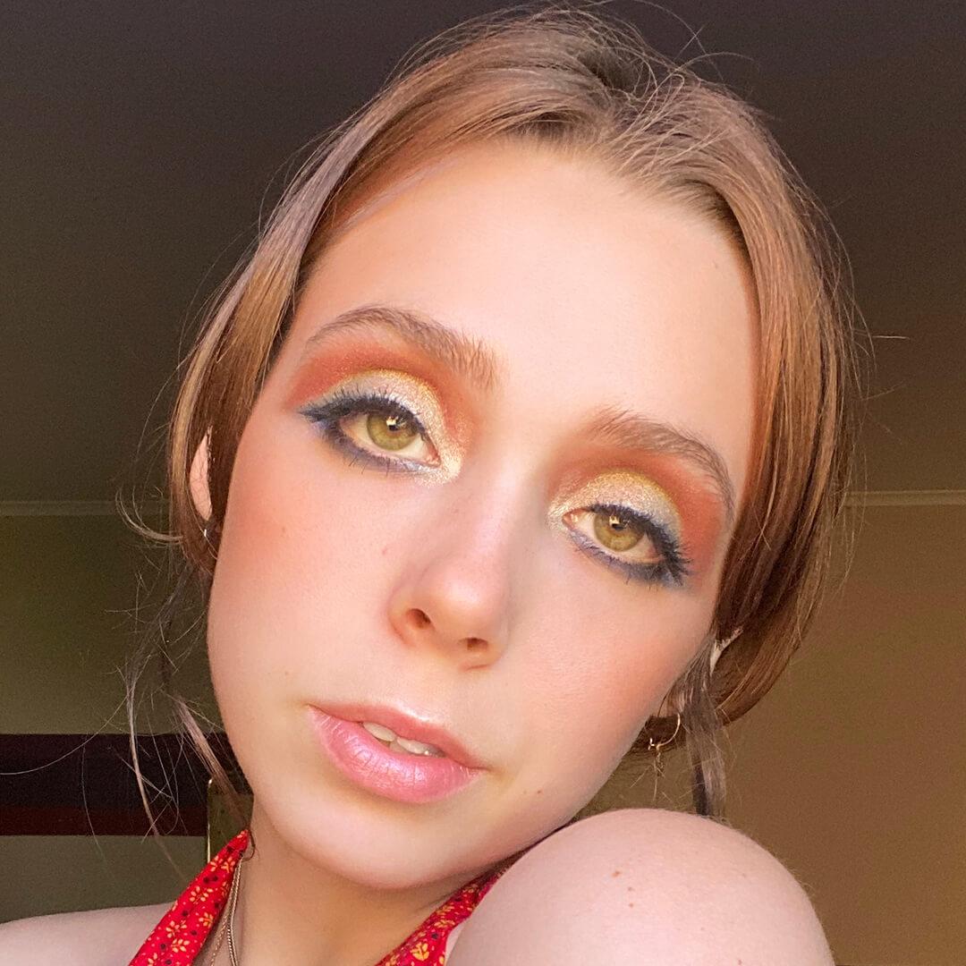 Devyn Severson in a room rocking a shimmery gold and matte orange eyeshadow look Mobile