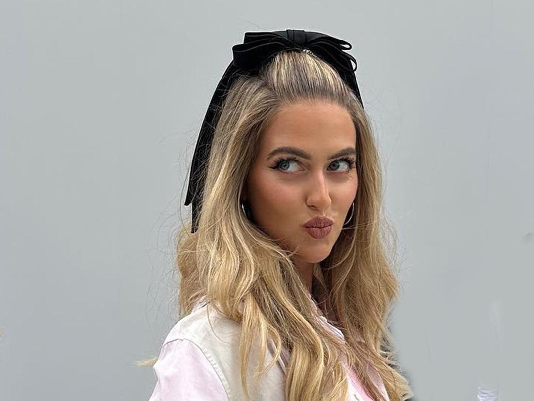 An image of a woman looking glam and chic with her black ribbon hairstyle