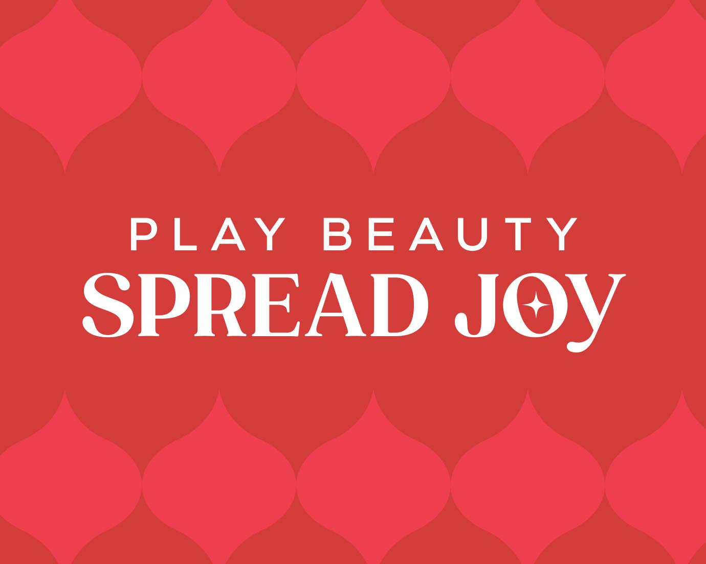 A red patterned graphic featuring the words “Play Beauty Spread Joy” in white, with bold, festive typography and a star accent inside the word “Joy.”