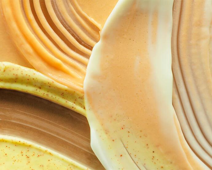 An image of a smudged, creamy texture in a mix of brown and yellow hues