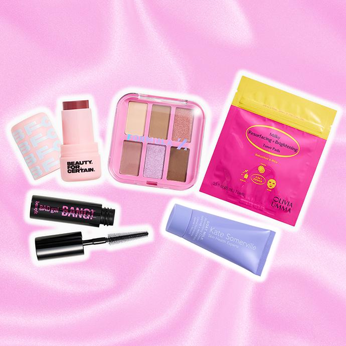 Curated beauty assortment featuring makeup and skincare favorites—including blush, eyeshadow, mascara, exfoliating toner pads, and nourishing moisturizer—set against a pink satin backdrop.