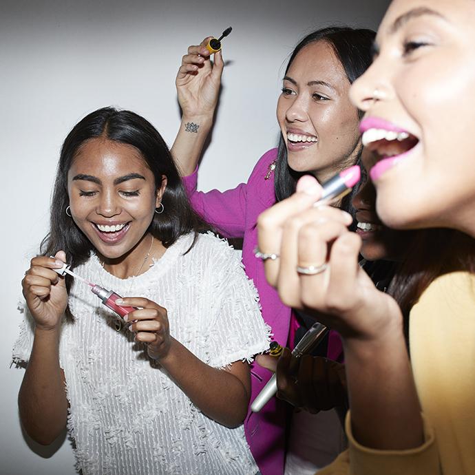 Cheerful friends doing make-up while enjoying in party at home