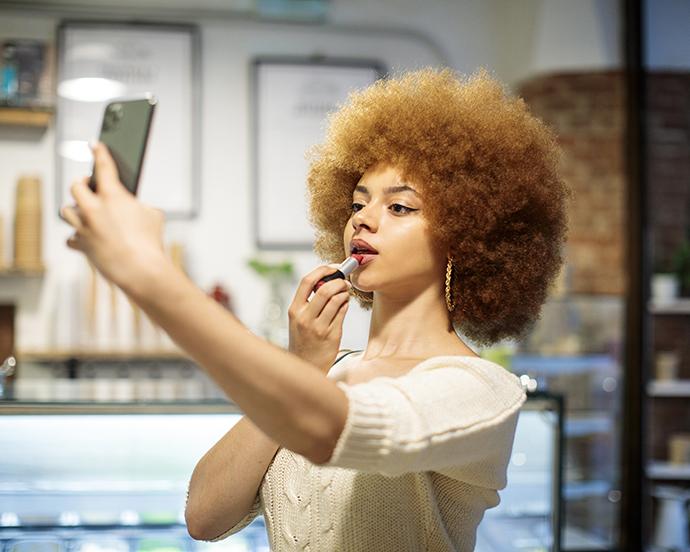 Social influencer making a video while putting on lip makeup