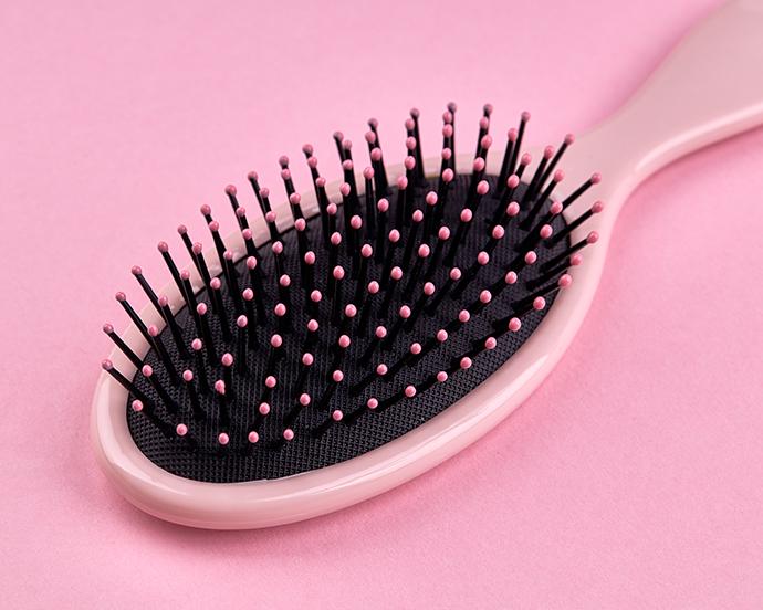 Pink hairbrush isolated on a pink coral background with space