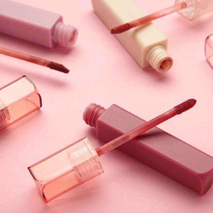 Beautiful lip glosses on a pink background. top view