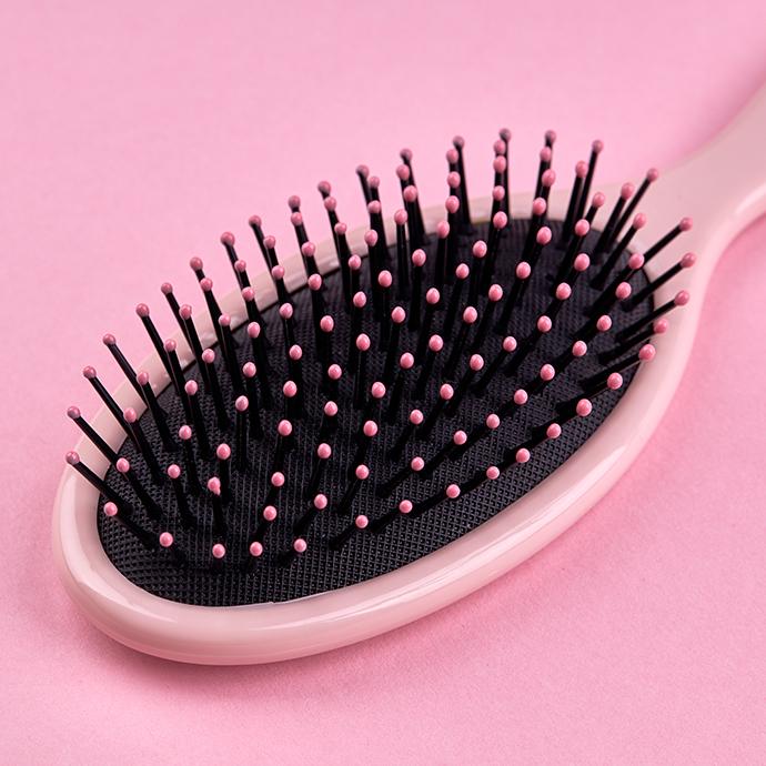 Pink hairbrush isolated on a pink coral background with space