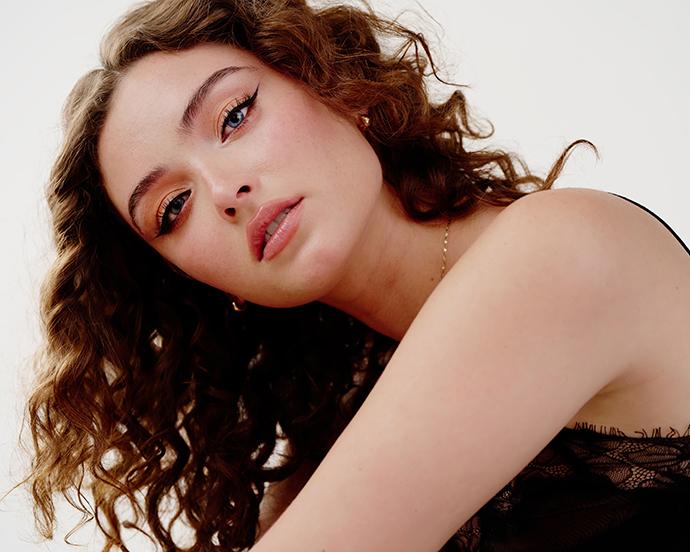 Model with natural air-dried curly hair and soft makeup, showcasing effortless texture and a low-maintenance hair routine