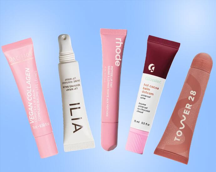 A row of colorful skincare tubes and a capsule-shaped product from brands Pacifica, Ilia, Rhode, Glossier and Tower 28 against a light blue background