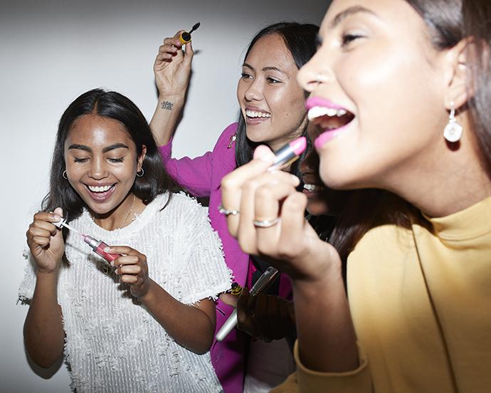 Cheerful friends doing make-up while enjoying in party at home