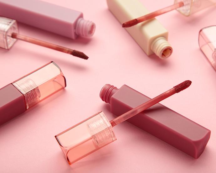 Beautiful lip glosses on a pink background. top view