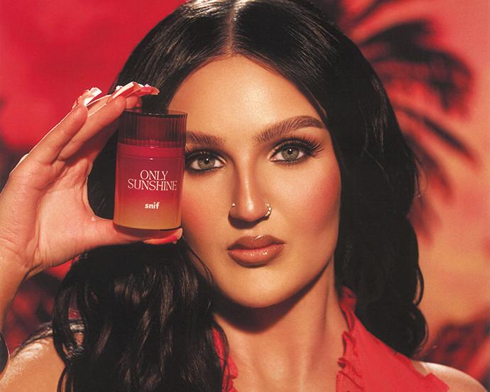 Mikayla Nogueira holding Snif Only Sunshine perfume, showcasing the vibrant summer fragrance with a warm, glowing makeup look.