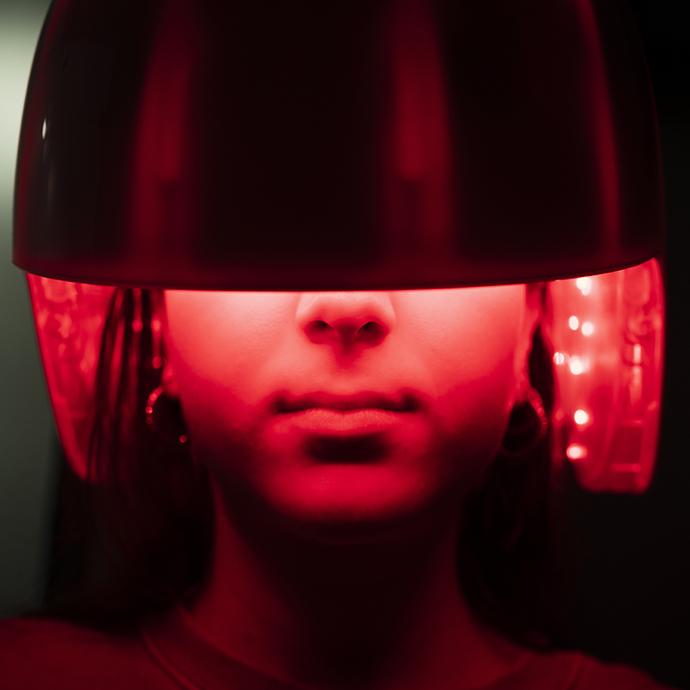 Young girl applying a led light treatment to her hair
