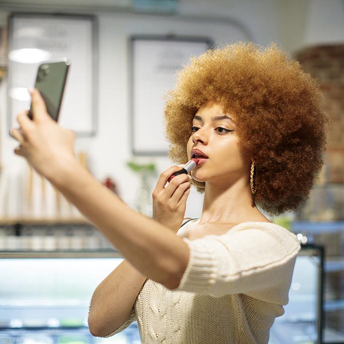 Social influencer making a video while putting on lip makeup