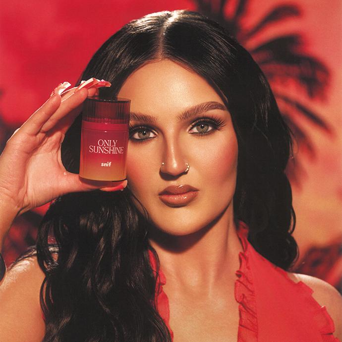 Mikayla Nogueira holding Snif Only Sunshine perfume, showcasing the vibrant summer fragrance with a warm, glowing makeup look.