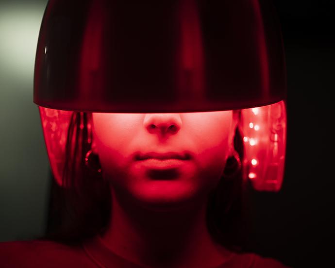 Young girl applying a led light treatment to her hair
