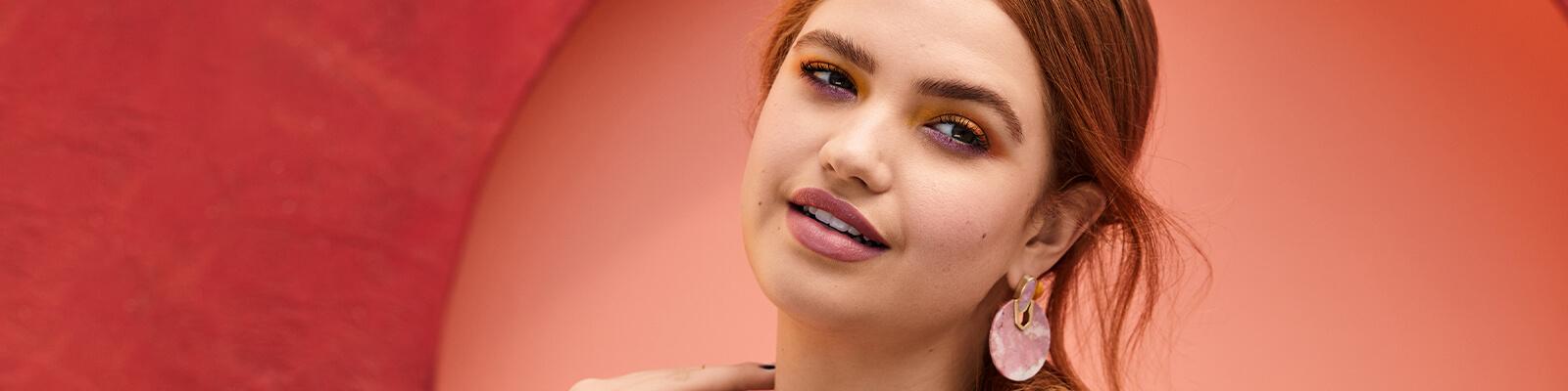 A model smiles against a red background. Desktop