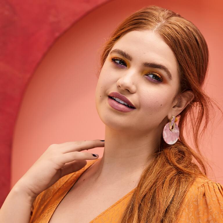 A model smiles against a red background. Mobile